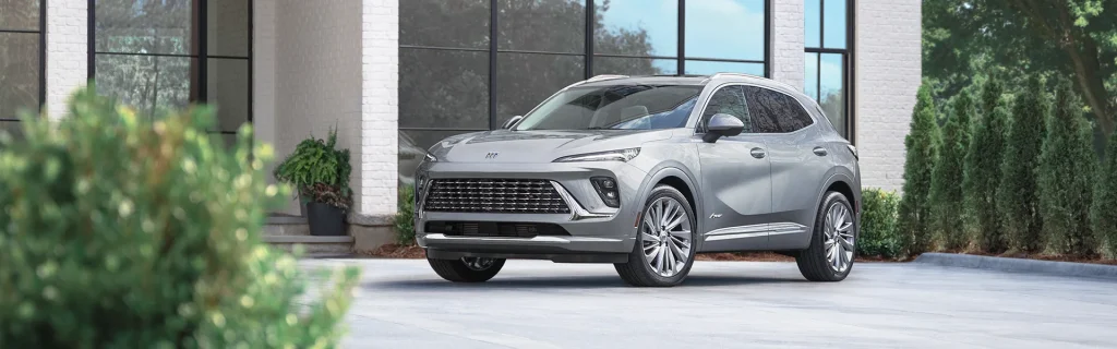 Silver Buick Envision SUV parked in front of a modern home.