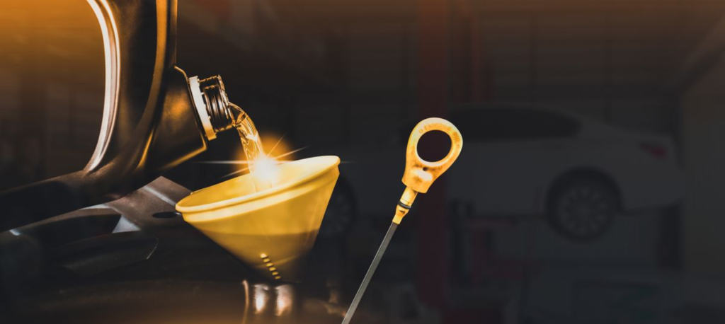 Motor oil being poured into an engine through a funnel during an oil change.