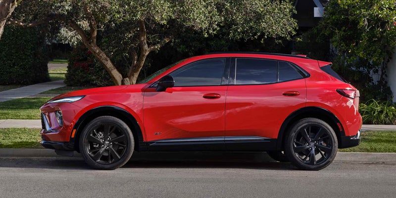 Red 2026 Buick Envision facing left near wooded area