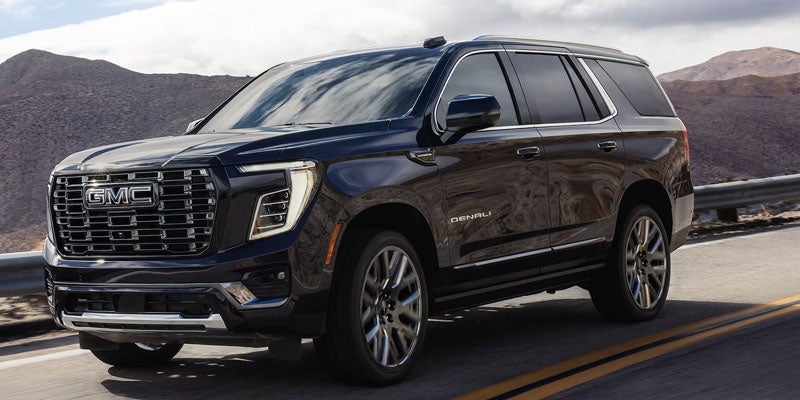 2026 black GMC Yukon driving on road near mountains in Goodyear, AZ